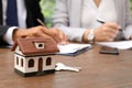 Keys and house model on table in real estate agent`s Royalty Free Stock Photo