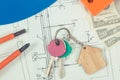 Keys with house shape, currencies dollar and electrical construction drawings with work tools. Building or buying home concept Royalty Free Stock Photo