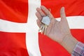 Keys to the apartment in a female hand on background of flag Denmark