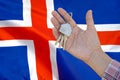 Keys to the apartment in a female hand on background of flag Iceland