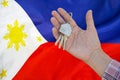 Keys to the apartment in a female hand on background of flag Philippines