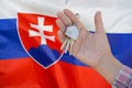 Keys to the apartment in a female hand on background of flag Slovakia