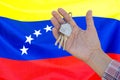 Keys to the apartment in a female hand on background of flag Venezuela