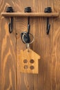 keys with a wooden keychain in form of a house hang in the hallway of the apartment. Real estate and security concept