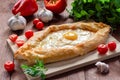 Khachapuri in Adjarian. Traditional Georgian cuisine. Open pie with Suluguni cheese and egg yolk in the shape of a boat on a woode