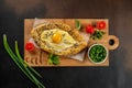 Khachapuri cheese and egg filled bread on a wooden board, top view. copy space