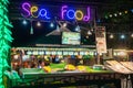 Khao Lak, Thailand, August 30, 2019: seafood neon restaurant sign and showcase with fresh fish on the street in a nightcap, Royalty Free Stock Photo