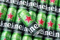 Many cans of Heineken alcoholic beer lie on a gray background.