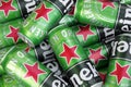 Many cans of Heineken alcoholic beer lie on a gray background.