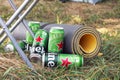 Many cans of Heineken alcoholic beer are set against the backdrop of an outdoor camp