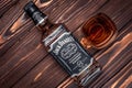Kharkiv, Ukraine, January 14, 2021: Full bottle of Jack Daniels No. 5 on a dark brown wooden boards. A glass of American whisky.