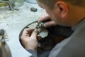 KHARKIV, UKRAINE - January 31, 2019: The master jeweler holds the working tool in his hands and makes jewelery at his workplace