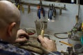 KHARKIV, UKRAINE - January 31, 2019: The master jeweler holds the working tool in his hands and makes jewelery at his workplace