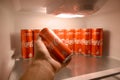 Male hand shows Coca-cola red drink can inside domestic cooler fridge full of coke cans Royalty Free Stock Photo