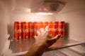 Male hand want to grab Coca-cola red drink can inside domestic cooler fridge full of coke cans Royalty Free Stock Photo