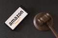 KHARKIV, UKRAINE - JUNE 25, 2020: Amazon logo on smartphone screen and wooden judge gavel. American international electronic