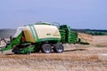 Kharkiv / Ukraine - June 27, 2019: A tractor combine harvester collects straw into bales after mowing rye wheat in an agricultural