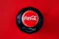 Kharkiv, Ukraine, November 14, 2019: Glass bottle of coca-cola on red background. Top view. Round cork with drops of water,