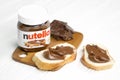 KHARKOV, UKRAINE - DECEMBER 27, 2020: Nutella glass can and spread on freshly baked bread. Nutella is manufactured by Italian