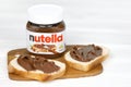 KHARKOV UKRAINE - DECEMBER 27 2020: Nutella glass can and spread on freshly baked bread. Nutella is manufactured by Italian