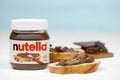 KHARKOV UKRAINE - DECEMBER 27 2020: Nutella glass can and spread on freshly baked bread. Nutella is manufactured by Italian