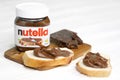 KHARKOV, UKRAINE - DECEMBER 27, 2020: Nutella glass can and spread on freshly baked bread. Nutella is manufactured by Italian