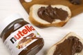 KHARKOV, UKRAINE - DECEMBER 27, 2020: Nutella glass can and spread on freshly baked bread. Nutella is manufactured by Italian