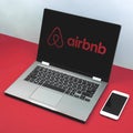 Kharkov, Ukraine - February 24, 2021: Airbnb logo on laptop screen, workspace with Apple iPhone smartphone, flat lay style Royalty Free Stock Photo