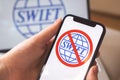 SWIFT blocked, logo close-up on mobile phone screen. Girl use S.W.I.F.T. banking and international technology concept