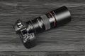 Canon EOS R photocamera and mount adapter EF - EOS R with Canon 105mm f2.8 lens on black wooden table. Photography equipment by
