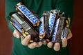 KHARKOV, UKRAINE - OCTOBER 8, 2019: A young caucasian brunette girl shows many Snickers chocolate bars in dark room. Snickers