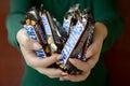 KHARKOV, UKRAINE - OCTOBER 8, 2019: A young caucasian brunette girl shows many Snickers chocolate bars in dark room. Snickers