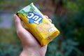 Tuc snack pack in male hand on a green trees background