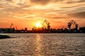 Kherson port at sunset Ukraine. View from the Dnieper River to the coastline with harbor cranes and commercial ships illuminated