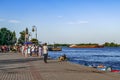 Many people walk on the Kherson Naberezhna, and a large cargo tanker is sailing in the Dnieper
