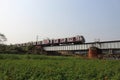 Khirai, West Bengal/India - January 1, 2020: Beautiful landscape of flower farming field and train leaving on a over bridge on a v