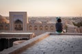 A lonely tourist sitting on the roof of one of houses in Old City of Khiva