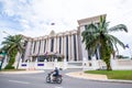 Khmer people riding motorcycle pass the Royal Government Hall of Cambodia on sunny day