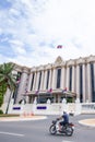 Khmer people riding motorcycle pass the Royal Government Hall of Cambodia on sunny day