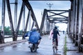 Khmer people riding motorcycles and bicycle across over the old French Bridge on rainy morning, Kampot, Cambodia Royalty Free Stock Photo