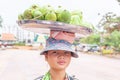 A Khmer young girl vendor carrying mangoes on the street at seaside