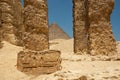 Khufu pyramid seen from ancient ruins. Pillars and stone fragment with Egyptian hieroglyphs