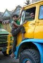 Khulna, Bangladesh: A young boy climbs on the cab of a truck in Khulna with the smiling driver inside