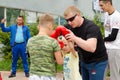 Kickboxing coach shows the boy how to make punch in sparring. Training outdoor in summer