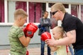 Kickboxing coach shows the boy how to make punch in sparring. Training outdoor in summer