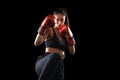 Kickboxing woman in activewear and red kickboxing gloves on black background performing a martial arts kick Royalty Free Stock Photo