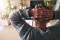 Kicking back for a bit. Rearview shot of a young man sitting with his hands behind his head while using a laptop at home Royalty Free Stock Photo