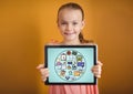 Kid against yellow wall holding tablet showing school doodles and blue background