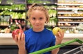 Kid with apple and shopping cart at grocery store. Shopping in supermarket. Kids buying groceries in supermarket. Little Royalty Free Stock Photo