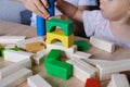 Kid, baby builds towers and buildings from colored wooden figures, the concept of housing construction, mortgage, insurance, happy Royalty Free Stock Photo